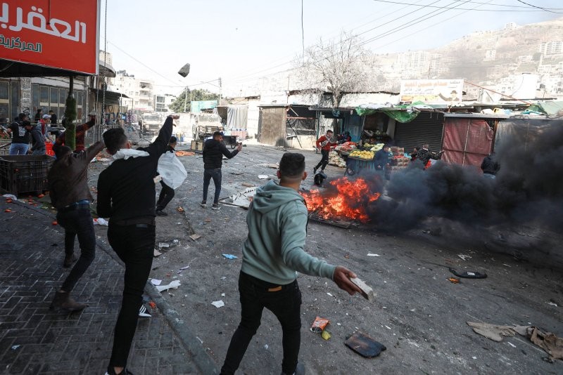 Người Palestine ném đá vào các phương tiện của quân đội Israel trong một cuộc đột kích ở thị trấn Nablus bị chiếm đóng ở Bờ Tây hôm thứ Tư