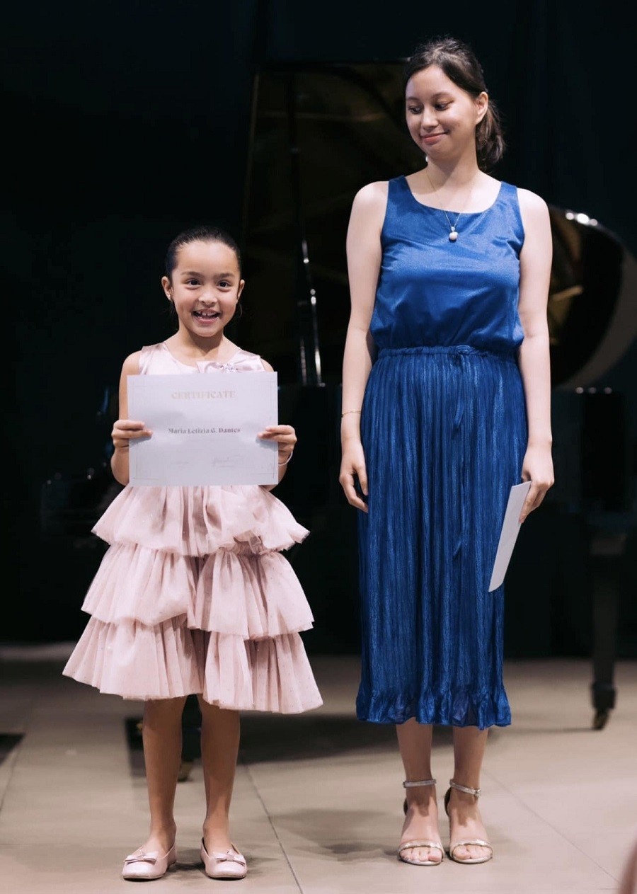 Bé gái nhận chứng chỉ sau bài biểu diễn.