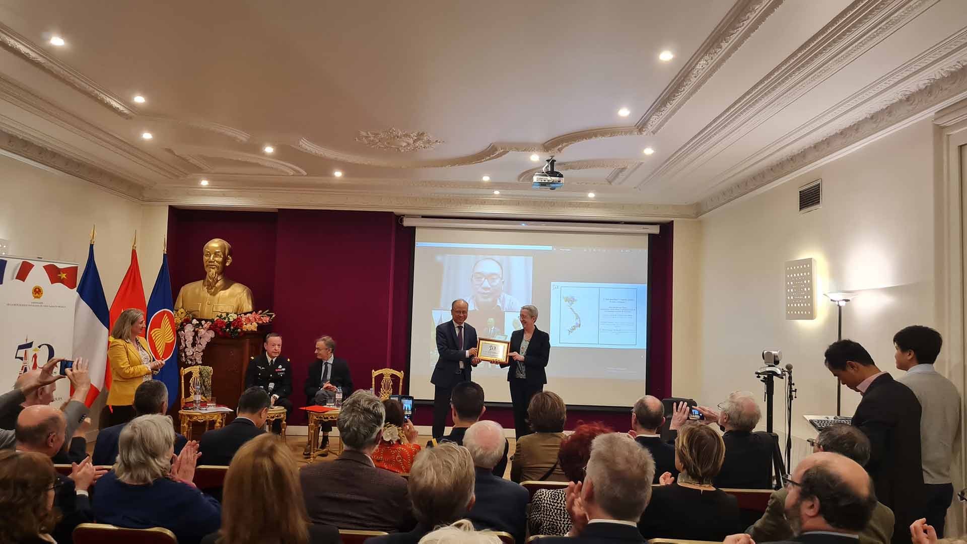 Đại sứ Đinh Toàn Thắng trao quà là bức tem có logo kỷ niệm 50 năm quan hệ Việt Nam-Pháp cho đại diện Ban Quan hệ quốc tế Học viện Nghiên cứu cao cấp quốc phòng.