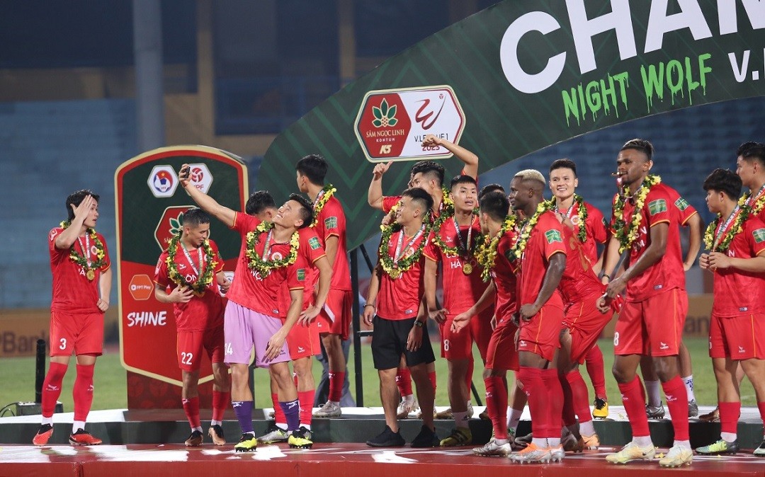 Thủ môn Bùi Tiến Dũng lấy điện thoại selfie với các đồng đội trên bục trao giải. Đây là chức vô địch V-League thứ hai của Bùi Tiến Dũng. Trước đó, anh từng vô địch V-League 2019 cùng Hà Nội FC. Dù vậy, ở cả hai mùa giải này, thủ thành gốc Thanh Hóa đều chỉ đóng vai trò dự bị. 