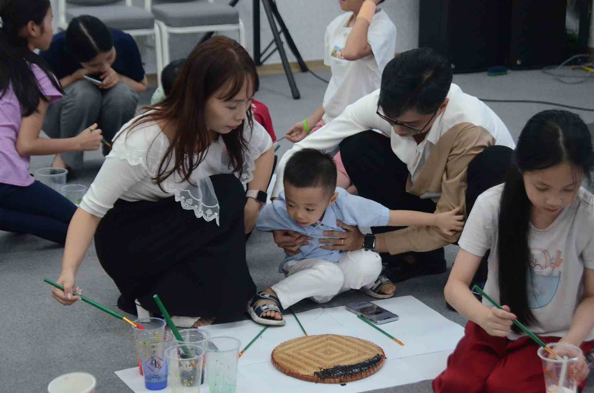 Các con cùng phụ huynh chơi trò chơi vẽ tranh lên mẹt tre.