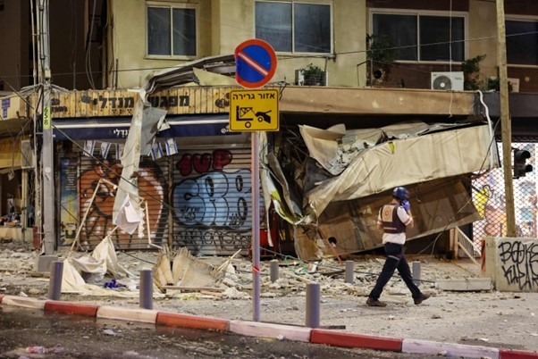 Một nhân viên cứu hộ Israel đi trước một cửa hàng bị hư hại ở Tel Aviv. (Nguồn: AFP) Một nhân viên cứu hộ Israel đi trước một cửa hàng bị hư hại ở Tel Aviv. (Nguồn: AFP)