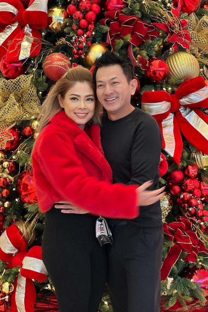 Thanh Thảo chụp ảnh bên ông xã trong dịp Noel. Nữ ca sĩ diện trang phục sắc đen đồng điệu với chồng, tạo điểm nhấn bằng chiếc áo khoác lông đỏ nổi bật.