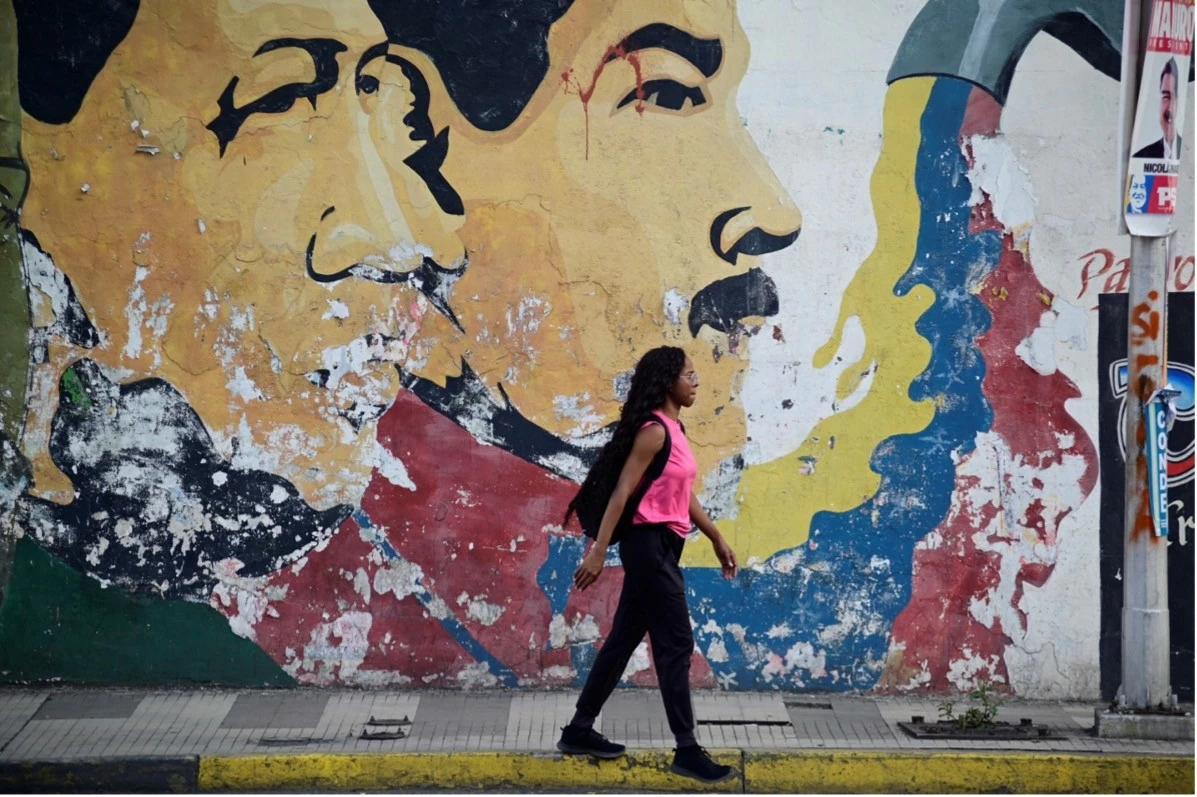 Một phụ nữ đi ngang qua bức tranh tường vẽ hình cố Tổng thống Venezuela Hugo Chavez và Tổng thống Venezuela Nicolas Maduro ở Caracas, Venezuela ngày 27/7. (Nguồn: Reuters) Một phụ nữ đi ngang qua bức tranh tường vẽ hình cố Tổng thống Venezuela Hugo Chavez và Tổng thống Venezuela Nicolas Maduro ở Caracas, Venezuela ngày 27/7. (Nguồn: Reuters)