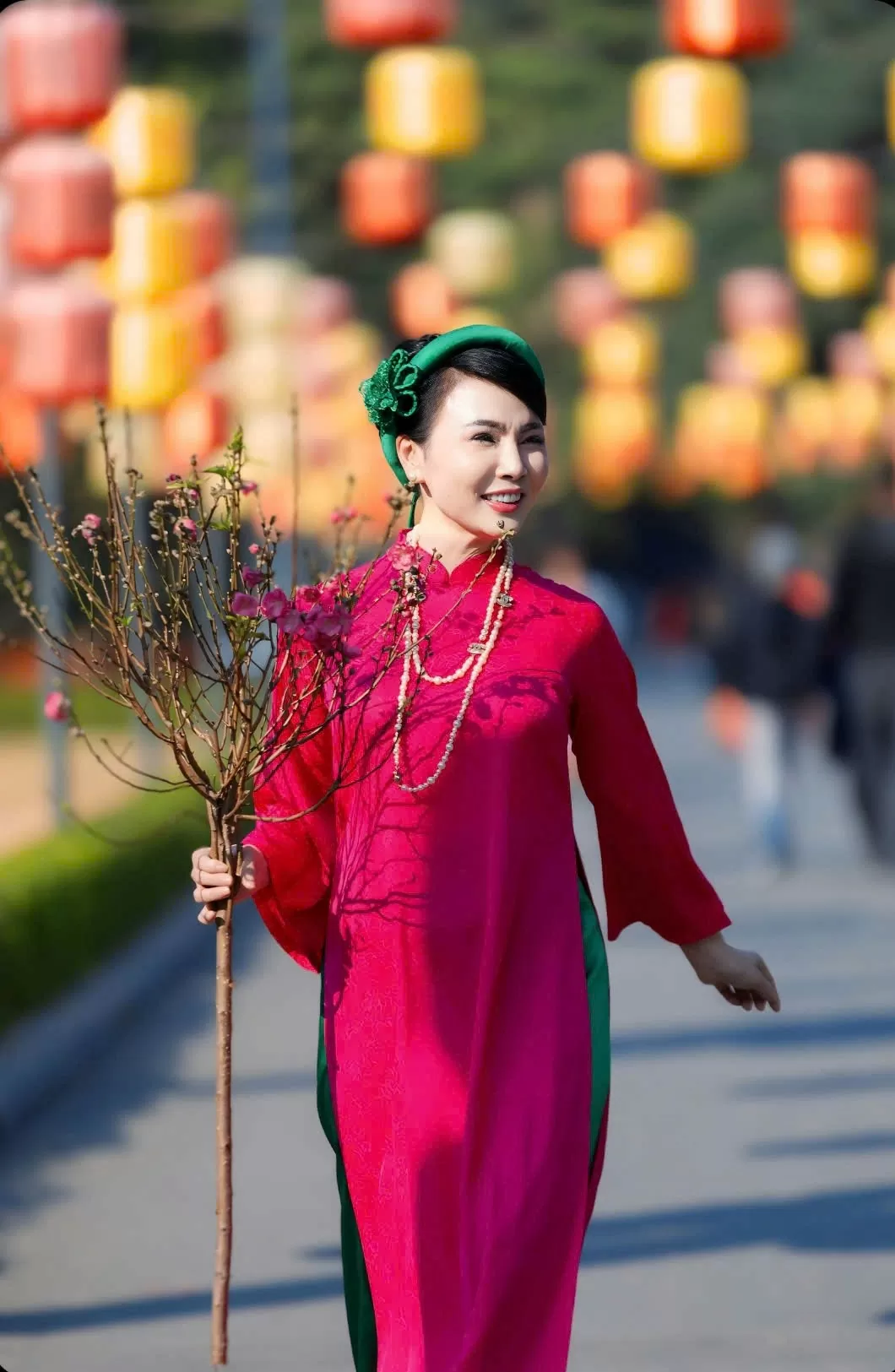 Bộ áo dài mang dáng dấp xưa cũ được thương hiệu thời trang Lydia thiết kế với tone màu sen và nhấn nhá màu xanh của lá sen trên mấn cách điệu cài đầu và chiếc quần lụa thướt tha, càng làm cho người mặc trở nên duyên dáng trong không gian đào mai sắm Tết.