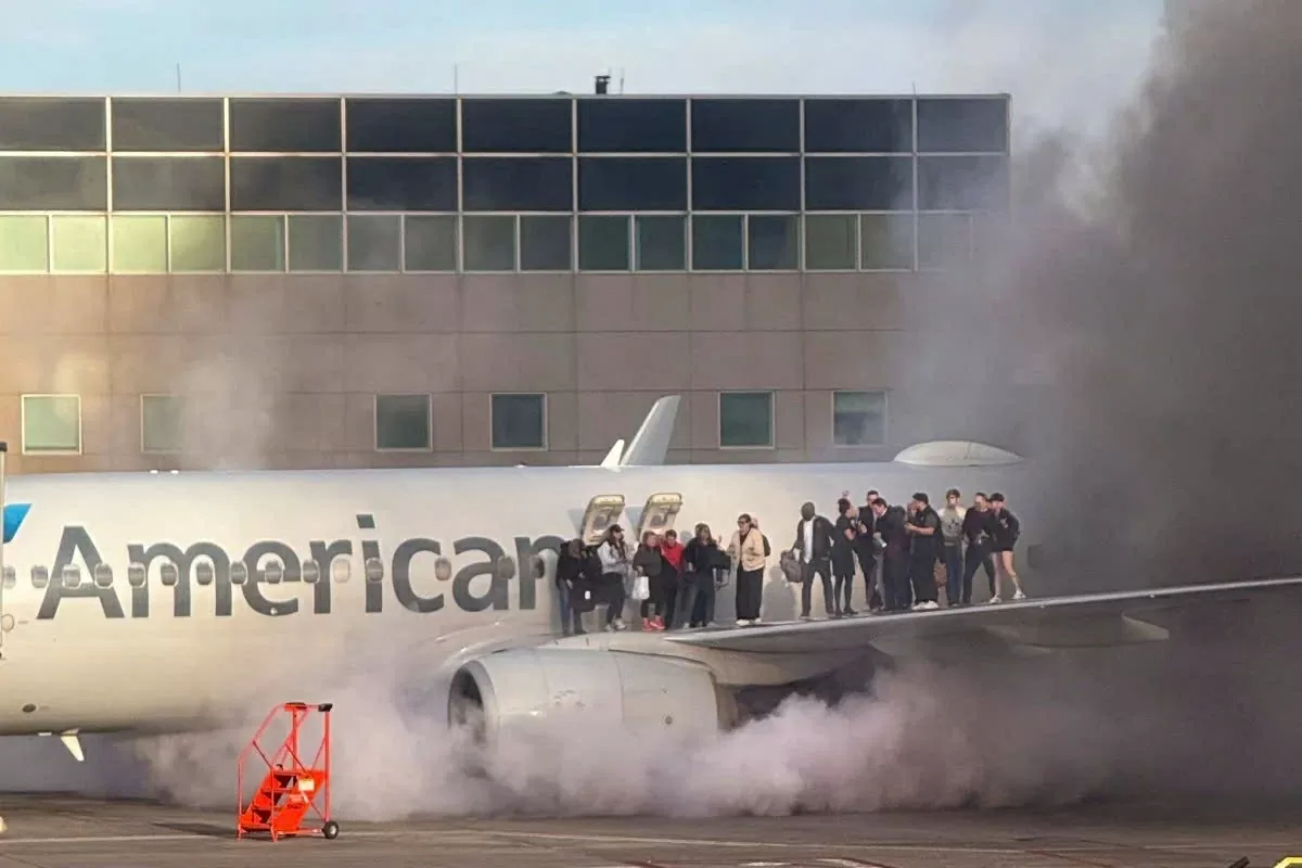 Hành khách đứng chờ sơ tán trên cánh của một chiếc máy bay American Airlines tại Sân bay Quốc tế Denver. (Nguồn: AFp)