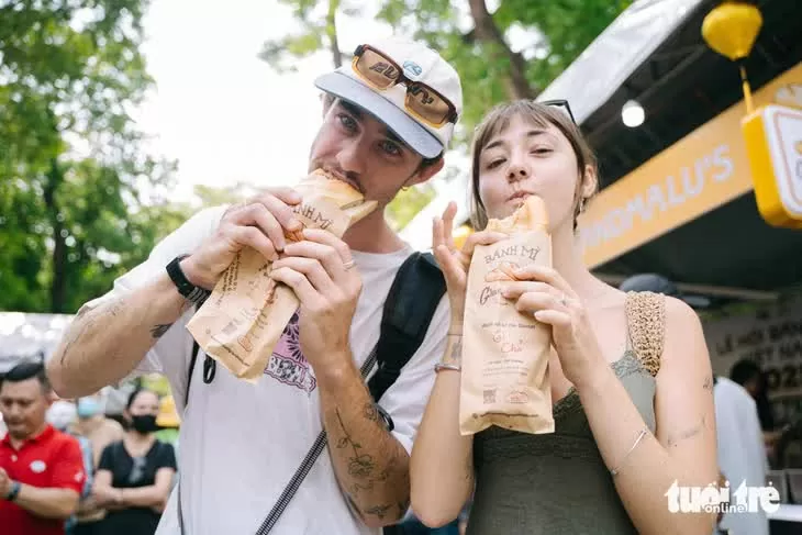 Du khách nước ngoài thưởng thức món bánh mì chả tại Lễ hội bánh mì Việt Nam lần 3 năm 2025. (Nguồn: Tuổi trẻ)