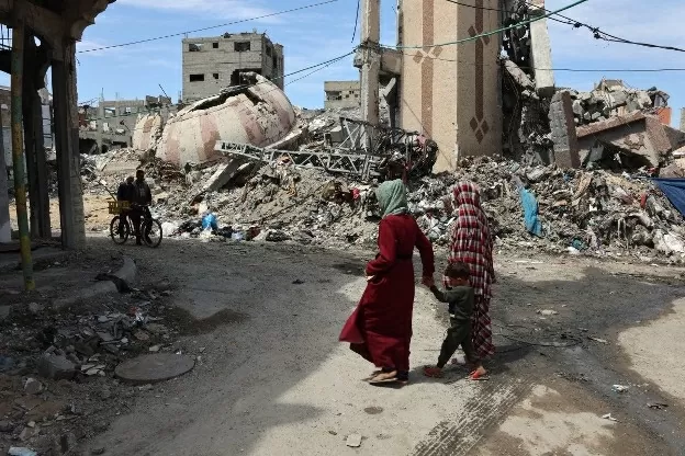 Người dân Palestine đi ngang qua đống đổ nát của các tòa nhà bị phá hủy trong cuộc tấn công ở Thành phố Gaza, ngày 28/3. (Nguồn: AFP)