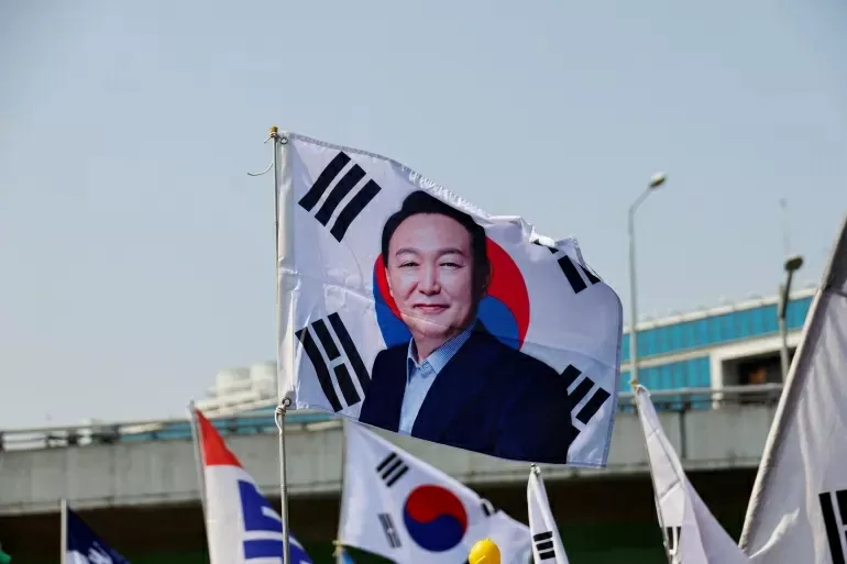 Những người ủng hộ giơ cao Quốc kỳ Hàn Quốc cùng bức ảnh của Tổng thống Yoon Suk-yeol  trong lúc chờ phán quyết của Tòa án Hiến pháp tại Seoul, ngày 4/4. Ngay sau đó, Tòa án Hiến pháp đã quyết định duy trì phán quyết luận tội ông Yoon Suk Yeol, bãi nhiệm ông khỏi chức vụ nguyên thủ quốc gia do ban bố lệnh thiết quân luật trong thời gian ngắn hồi tháng 12/2024. Phán quyết yêu cầu đất nước phải tổ chức một cuộc bầu cử tổng thống bất thường để chọn người kế nhiệm ông Yoon Suk Yeol trong vòng 60 ngày. Theo hãng tin Yonhap, nhiều khả năng cuộc bầu cử diễn ra vào ngày 3/6. (Nguồn: Reuters)