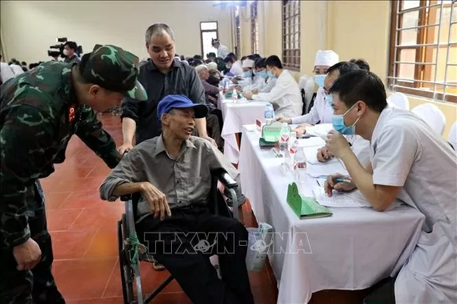 Tình nguyện viên hỗ trợ một người dân di chuyển bằng xe lăn ở thị trấn Đồng Đăng, huyện Cao Lộc, tỉnh Lạng Sơn đến bàn khám bệnh.