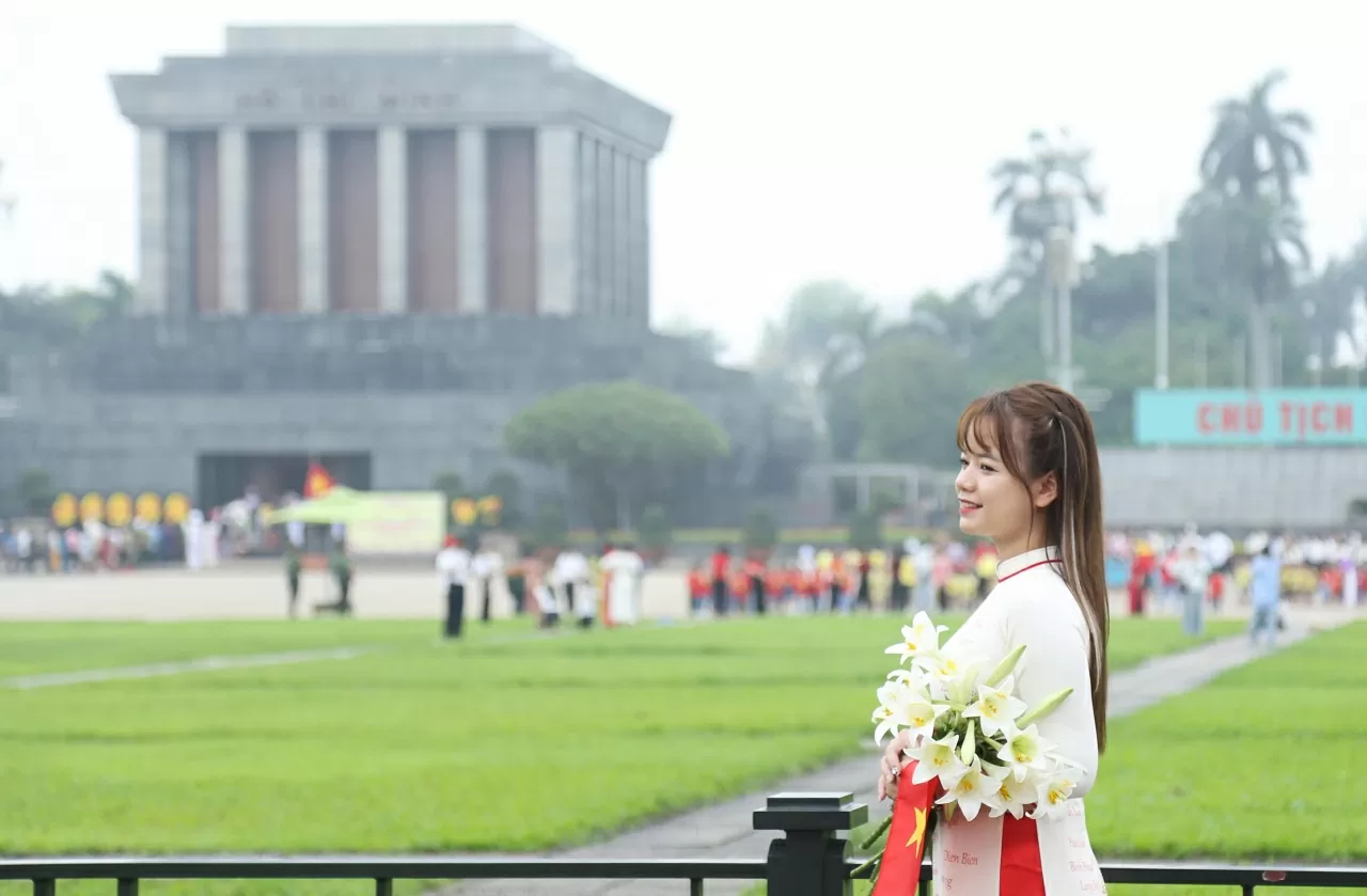 Các bạn trẻ cầm trên tay lá cờ tổ quốc cùng tà áo dài nền nã lưu giữ những khoảnh khắc kỷ niệm. (Ảnh: Thành Long)