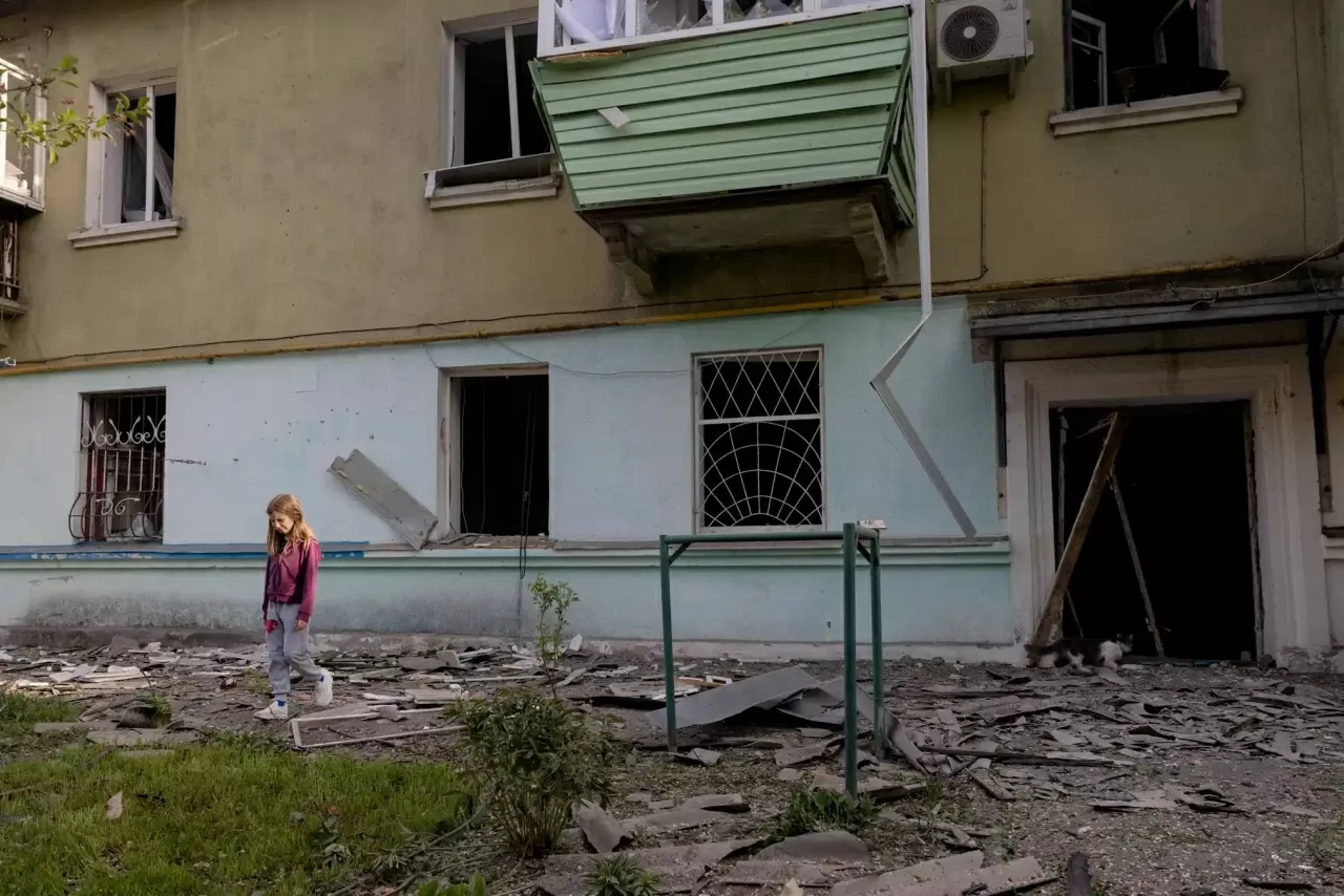 Một bé gái đi ngang qua ngôi nhà bị hư hại của mình sau một cuộc tấn công bằng tên lửa của Nga ở Kiev. (Nguồn: Reuters)