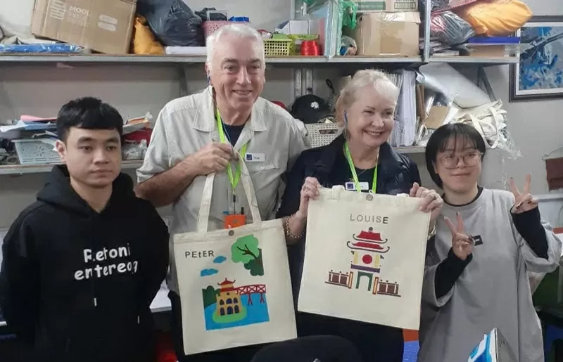 Ông Peter Didier (thứ hai từ trái qua) cùng chiếc túi tranh ghép vải lụa. 
