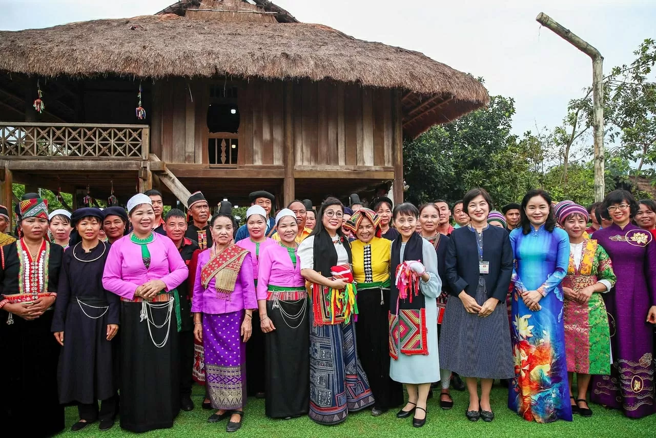 Đại diện đồng bào các dân tộc phía Bắc chào đón hai vị khách quý vào làng, giới thiệu về nhà sàn truyền thống của người Thái, về khau cút trên mái nhà.