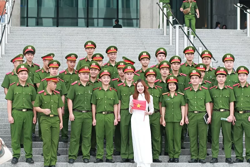 Nữ du khách mặc áo dài trắng giữa hàng ngũ cán bộ công an tại Bảo tàng Lịch sử Quân sự Việt Nam.