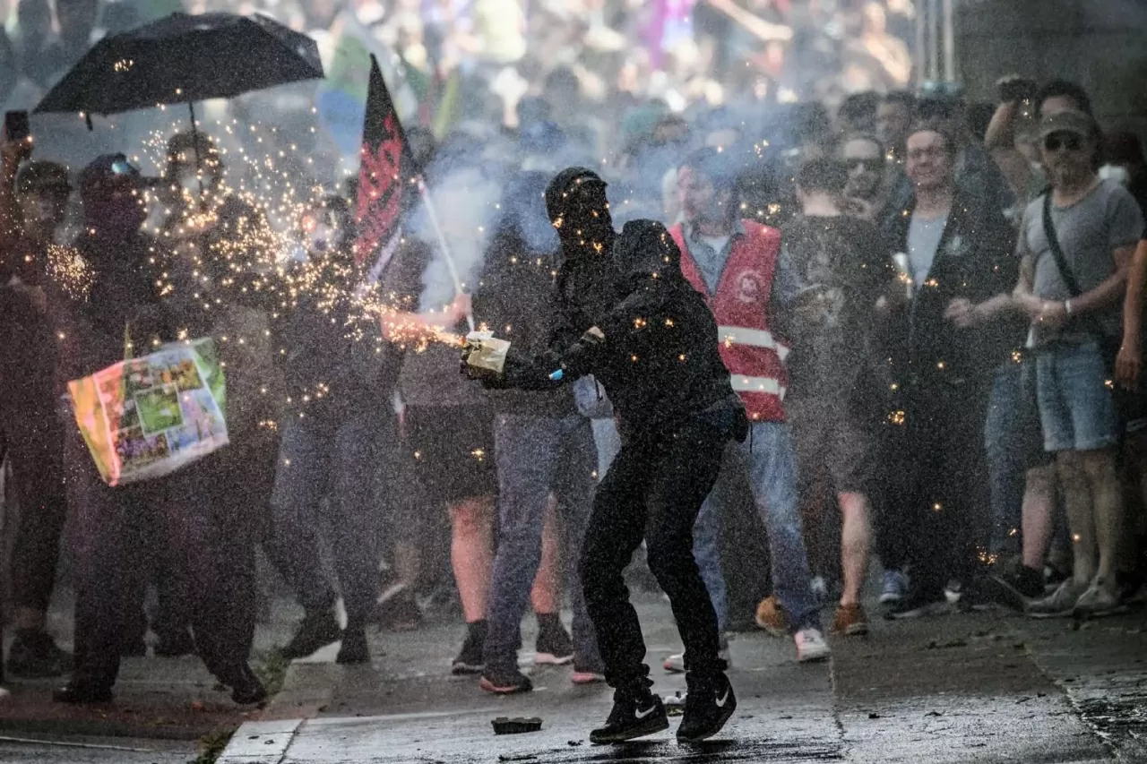 Một người biểu tình bị vòi rồng xịt nước khi ném pháo sáng về phía cảnh sát chống bạo động trong cuộc tuần hành nhân Ngày Quốc tế Lao động (1/5). (Nguồn: Getty Images)