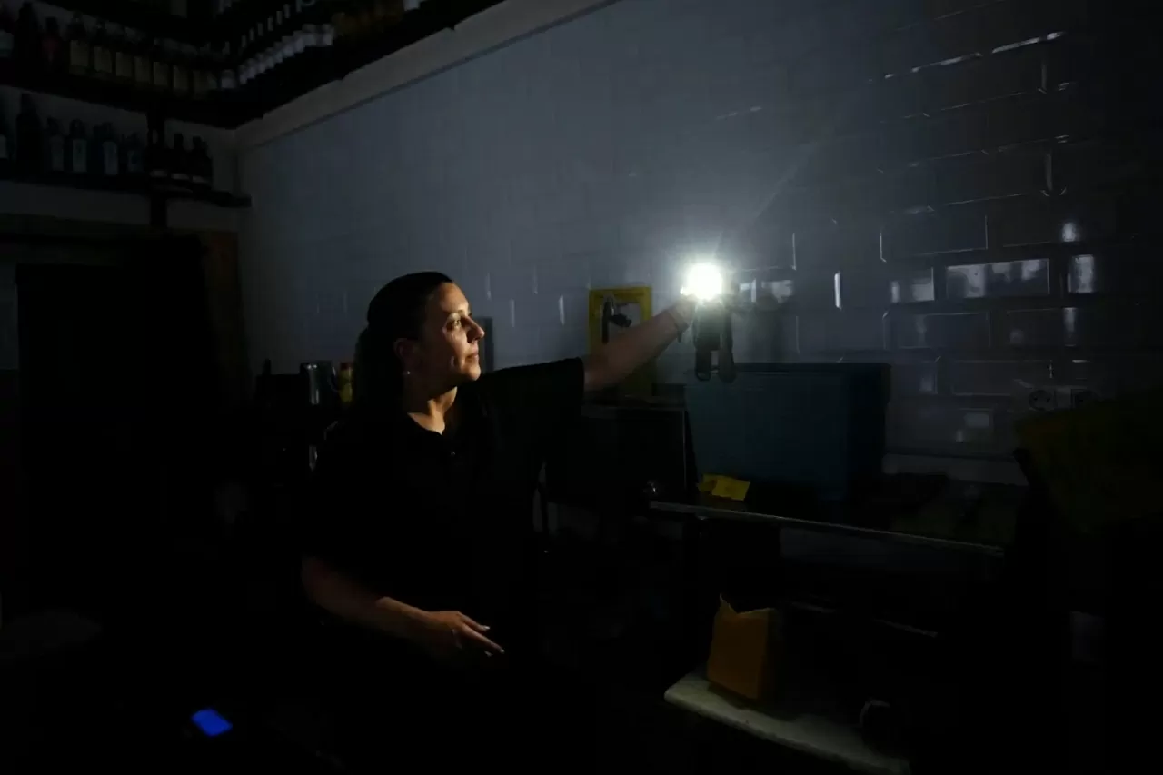 Một người phụ nữ sử dụng đèn pin điện thoại trong cửa hàng giữa lúc mất điện trên diện rộng tại Madrid, Tây Ban Nha. Ngày 28/4, cả Tây Ban Nha và Bồ Đào Nha bất ngờ bị mất điện diện rộng, khiến hệ thống tàu điện ngầm, tàu hỏa ngừng hoạt động, mạng di động và Internet tê liệt, máy ATM vô hiệu và giao thông hỗn loạn do đèn tín hiệu giao thông không hoạt động. Sự cố kéo dài 6-8 tiếng đồng hồ, thậm chí còn ảnh hưởng tới một số khu vực ở Pháp. (Nguồn: EPA)