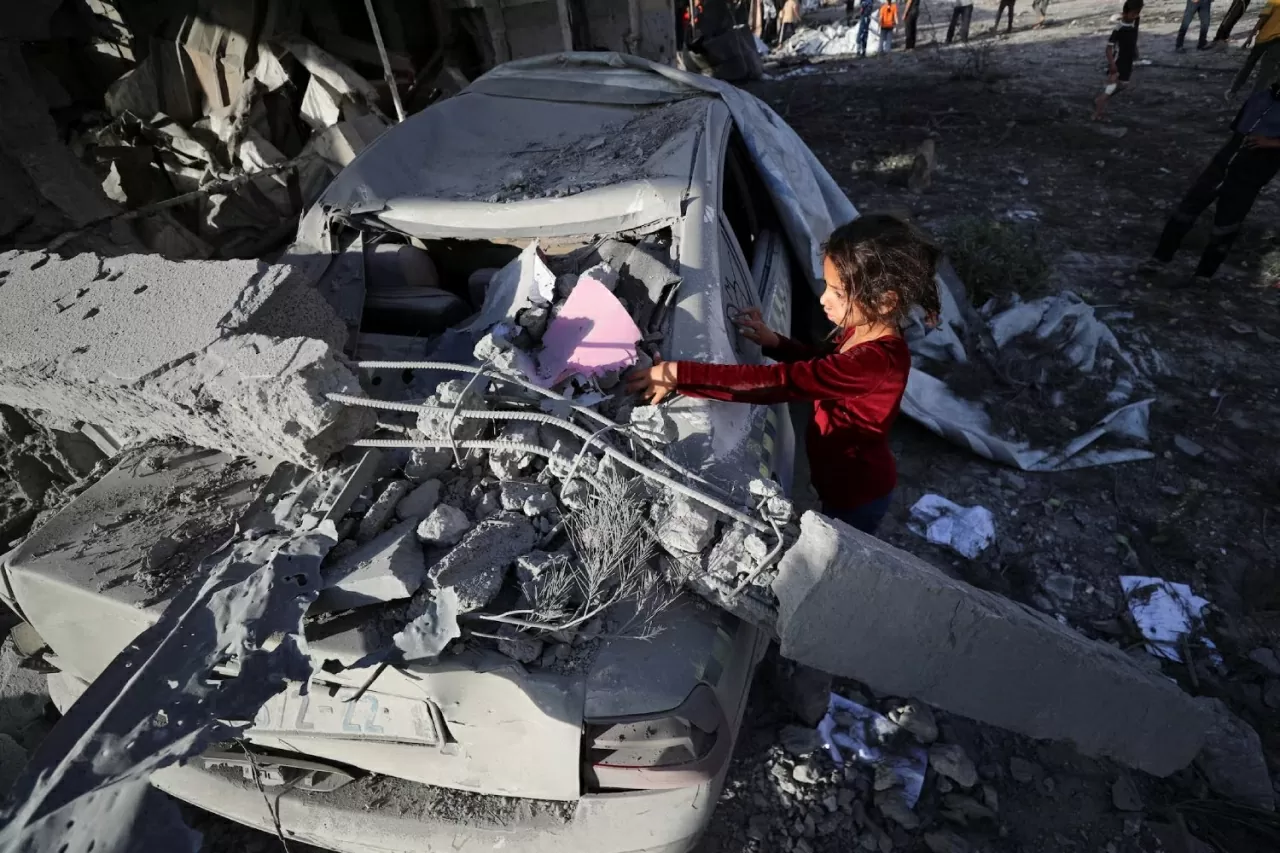Một bé gái Palestine vẽ nguệch ngoạc lên một chiếc ô tô bị hư hỏng tại hiện trường vụ không kích của Israel nhằm vào một ngôi nhà ở Jabalia, phía bắc Dải Gaza, ngày 14 tháng 5. (Nguồn: Reuters)