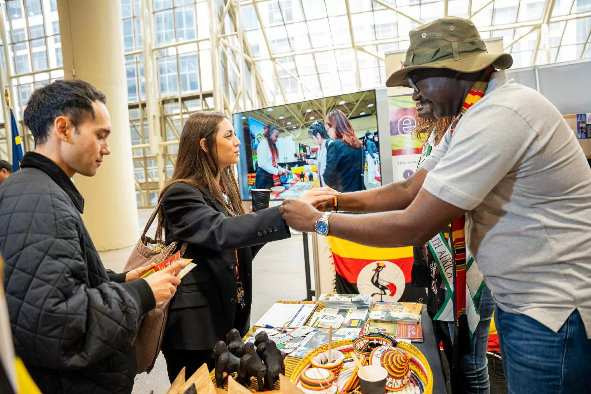 Khách tham quan gian hàng được mời uống cà phê hữu cơ, tặng vòng đeo tay thủ công, tìm hiểu về Uganda. (Nguồn: The New Vision)