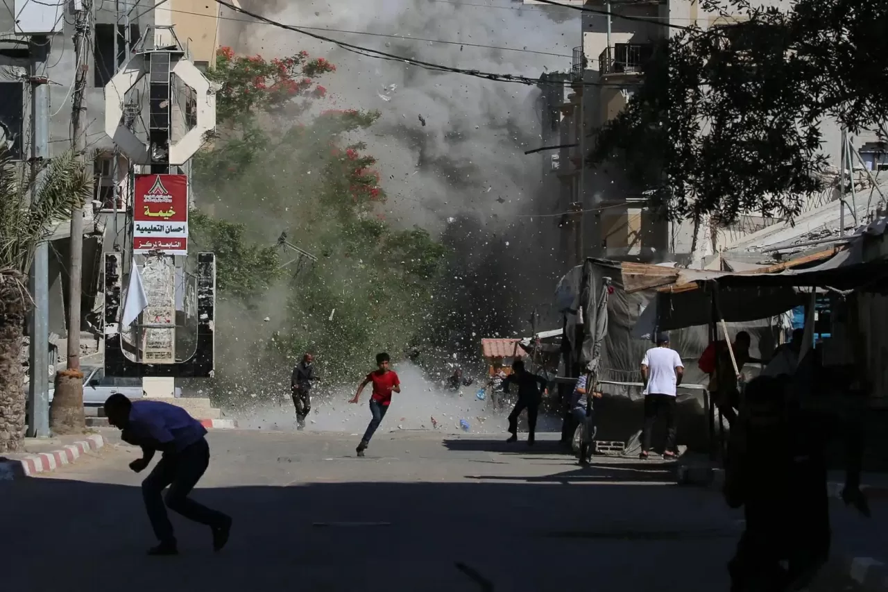 Người Palestine chạy tìm nơi ẩn nấp khi các mảnh vỡ bay tứ tung sau một cuộc không kích của Israel nhằm vào trại tị nạn Bureij ở trung tâm Dải Gaza. Ít nhất tám người Palestine đã thiệt mạng và hàng chục người khác bị thương hôm Chủ nhật trong các vụ nổ súng gần các điểm phân phát lương thực tại Gaza. Cư dân địa phương cho biết các cuộc tấn công của Israel đã leo thang, song song với xung đột mới với Iran. (Nguồn: Getty Images)