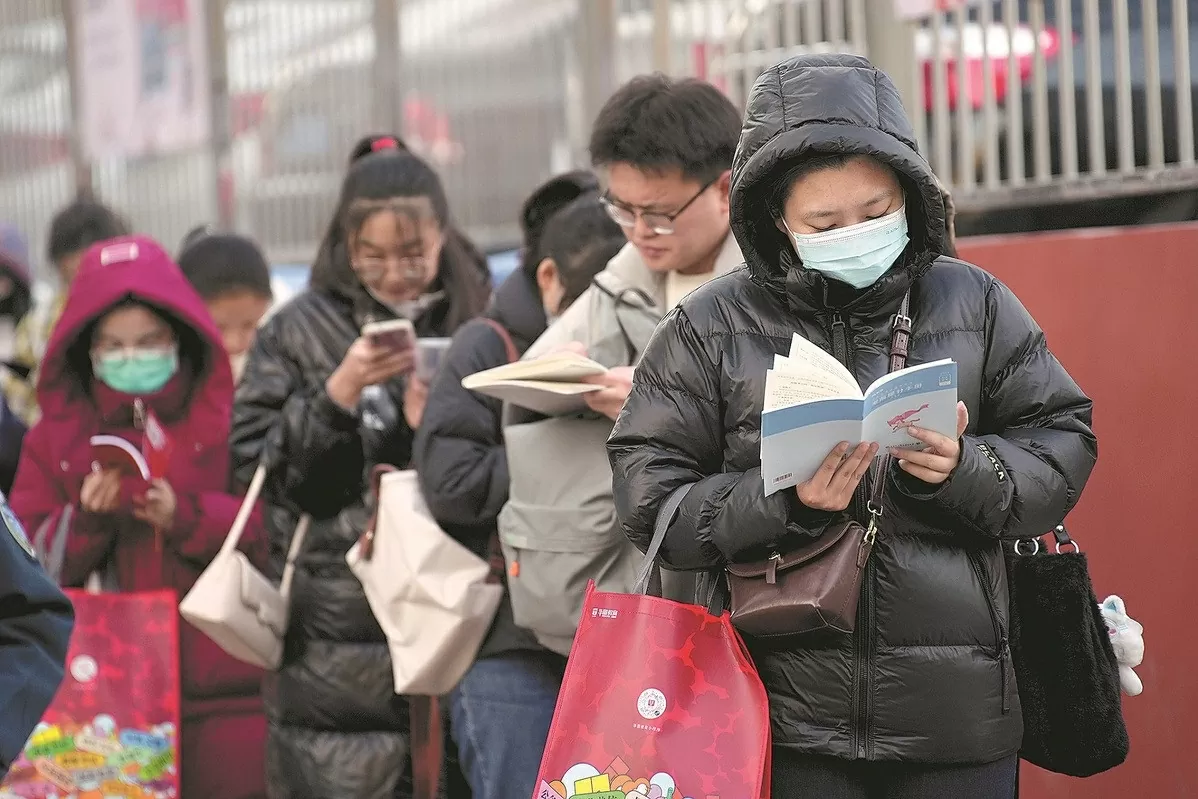 Các thí sinh tranh thủ xem lại tài liệu ôn tập lần cuối trước khi bước vào điểm thi kỳ thi công chức quốc gia tại Thái Nguyên, tỉnh Sơn Tây, Trung Quốc (ngày 26/11/2023). Ảnh: China News Service