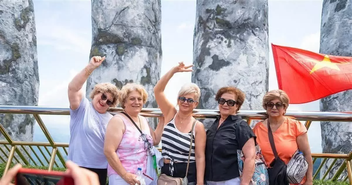 Du khách nước ngoài thích thú check-in với cây cầu Vàng được trang hoàng rực rỡ cờ Tổ quốc tại khu du lịch. (Nguồn: TTXVN) Du khách nước ngoài thích thú check-in với cây cầu Vàng được trang hoàng rực rỡ cờ Tổ quốc tại khu du lịch. (Nguồn: TTXVN)