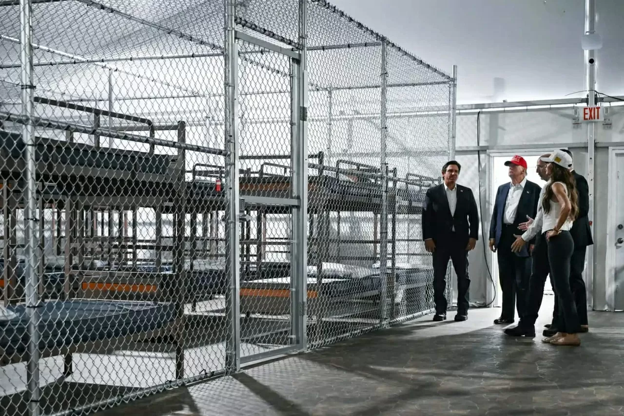 Thống đốc Florida Ron DeSantis (trái) cùng Tổng thống Donald Trump (thứ hai từ trái sang) và Bộ trưởng An ninh Nội địa Mỹ Kristi Noem (phải) thị sát một trại giam giữ người nhập cư không giấy tờ ở Ochopee, Florida vào ngày 1/7. Cơ sở này, được mệnh danh là “Alcatraz giữa vùng đầm lầy”, nằm giữa vùng Everglades rộng lớn phía nam bang Florida, nơi diễn ra các hoạt động giam giữ, xử lý và trục xuất người di cư. Tại cuộc họp báo sau chuyến thị sát, ông Trump gạt bỏ những lo ngại về điều kiện thời tiết khắc nghiệt tại vùng đầm lầy Everglades, nơi chỉ số nhiệt thường xuyên vượt ngưỡng 37,8°C vào tháng 7. (Nguồn: Getty Images)
