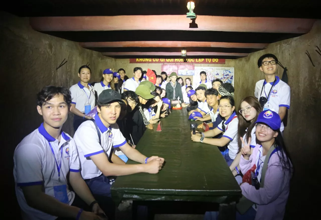 Các kiều bào trẻ chụp bức ảnh lưu niệm tại phòng chỉ huy nằm trong lòng Địa đạo Củ Chi. (Ảnh: Thành Long)