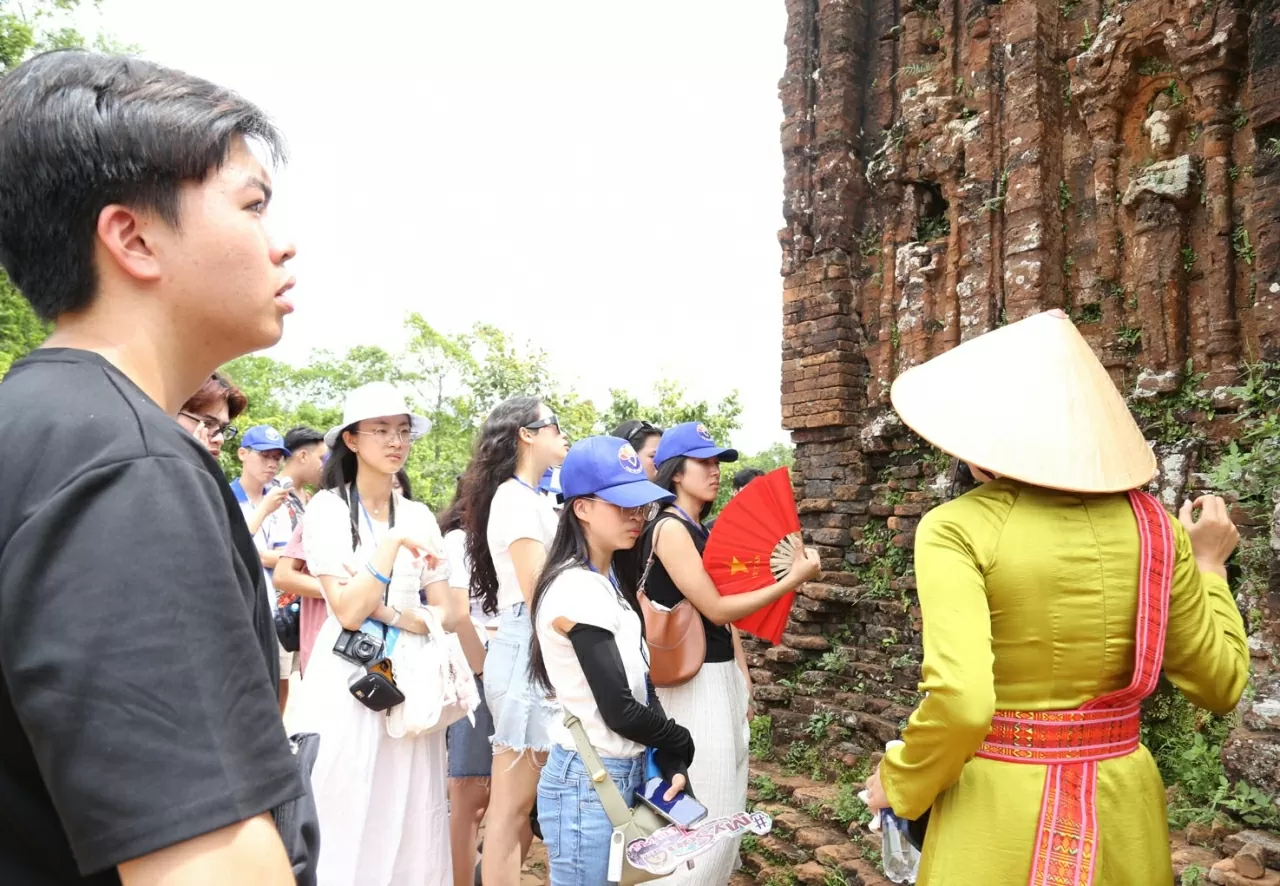 Nguyễn Bá Bảo, kiều bào từ Pháp (áo đen) nghe hướng dẫn viên giới thiệu về Thánh địa Mỹ Sơn. (Ảnh: Thành Long)