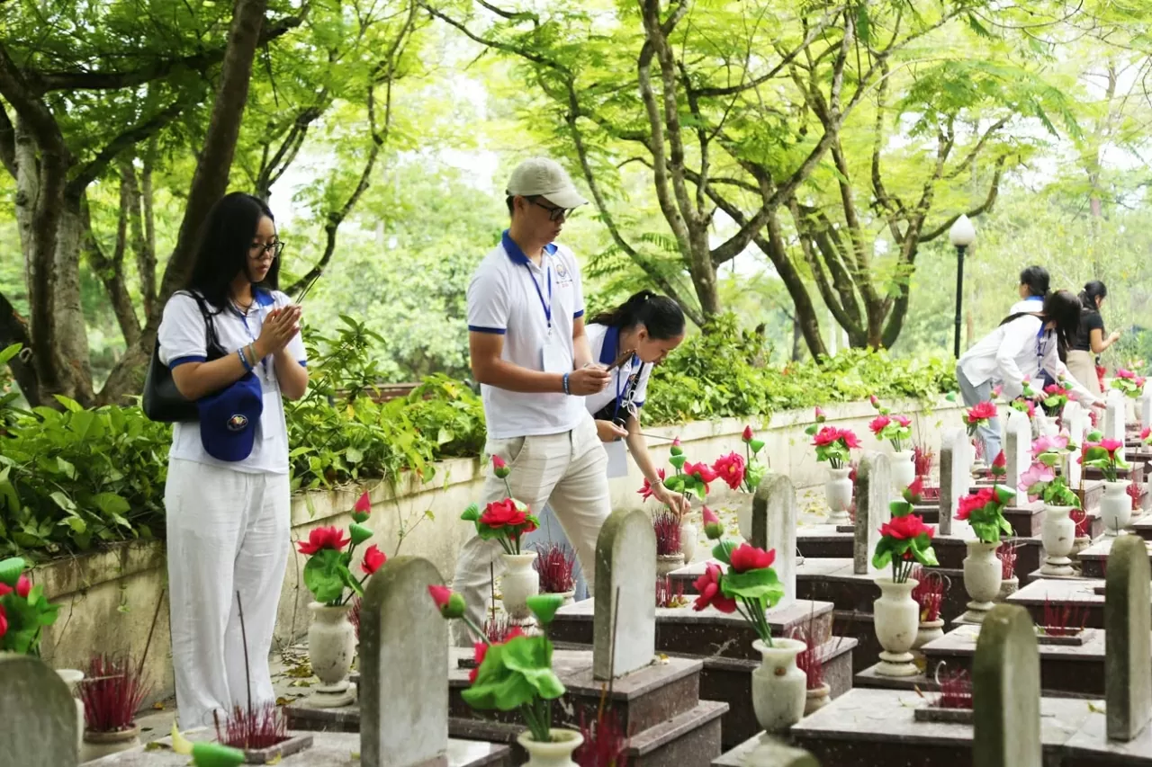 Các kiều bào trẻ thắp nén hương cho các ngôi tại mộ Nghĩa trang liệt sĩ vô danh. (Ảnh: Thành Long)