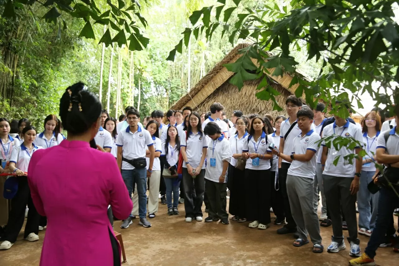Các thanh niên, sinh viên kiều bào được hướng dẫn viên kể về được biết thêm về những năm tháng thời niên thiếu của Bác Hồ tại quê nhà. (Ảnh: Thành Long)