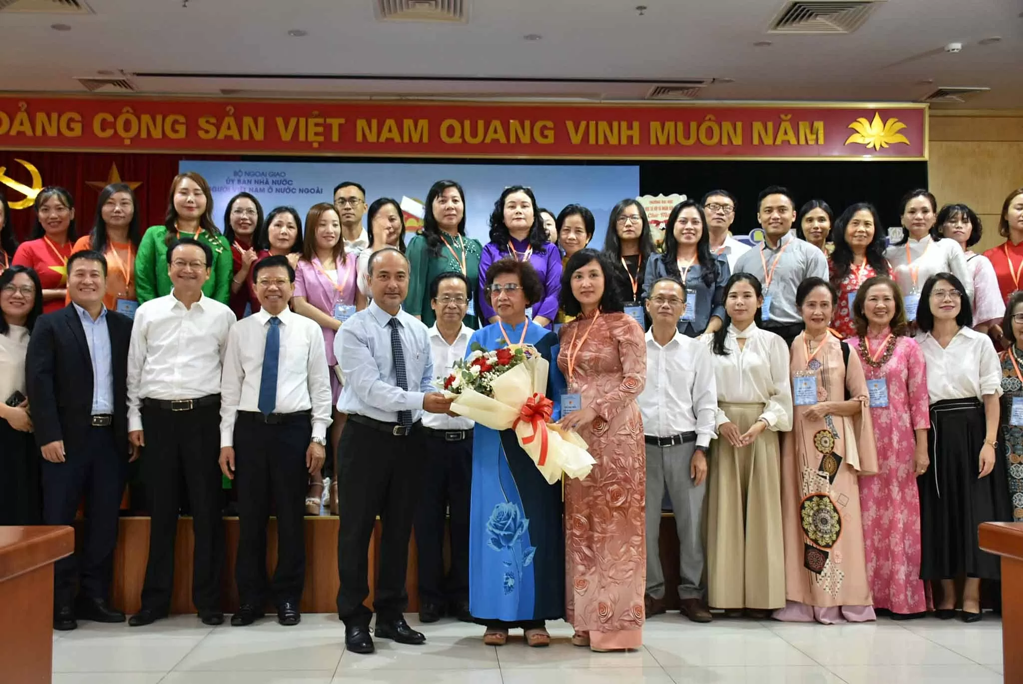 Cô Đỗ Bích Thảo, giáo viên tiếng Việt tại Ba Lan thay mặt các học viên tham gia khoá tập huấn nhận hoa chúc mừng của Chủ nhiệm Ủy ban Nhà nước về NVNONN Nguyễn Trung Kiên, ngày 14/8/2025. (Ảnh: Dương Tiêu)