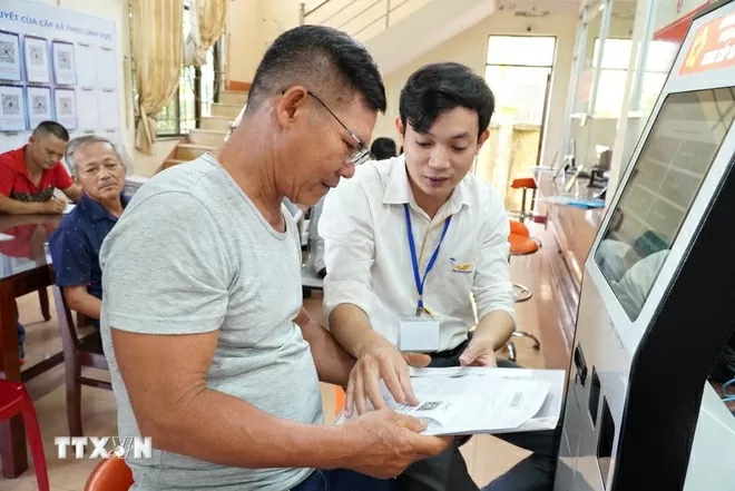 Cán bộ hướng dẫn người dân thực hiện thủ tục hành chính. (Ảnh: Đinh Hương/TTXVN)