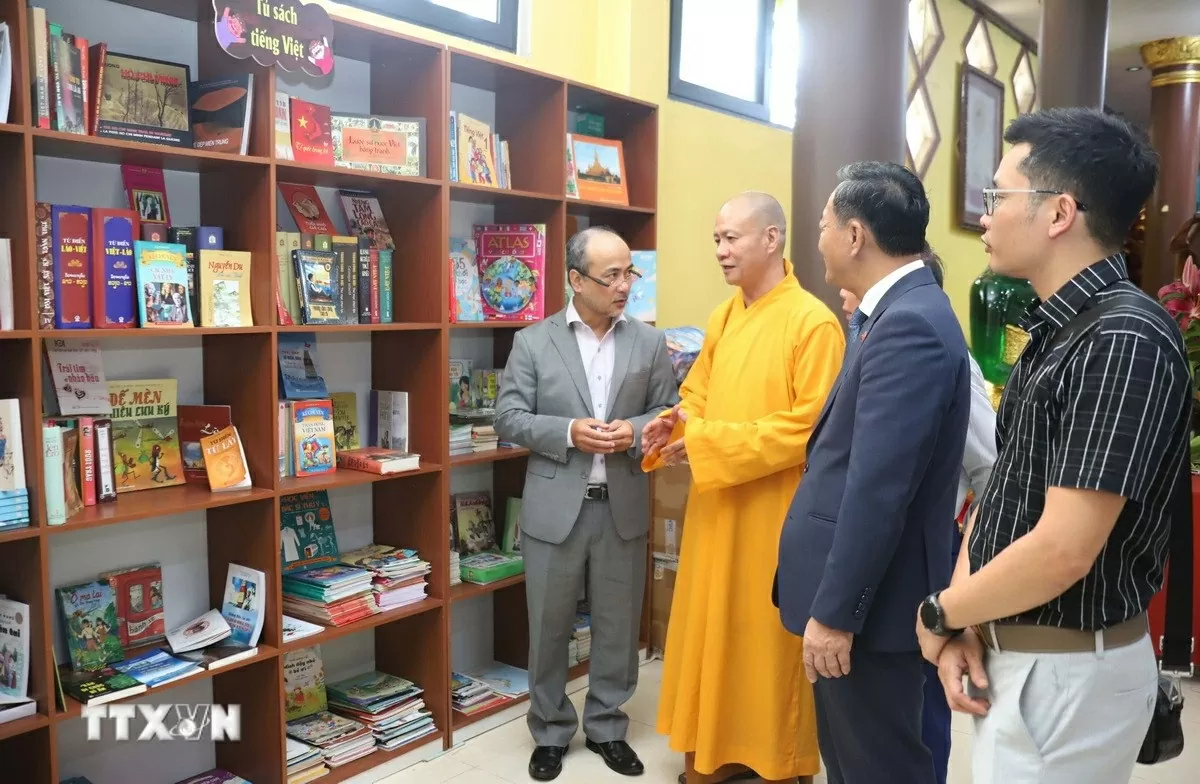 Trụ trì Chùa Phật Tích Thủ đô Vientiane giới thiệu về tủ sách. (Ảnh: Xuân Tú/TTXVN)