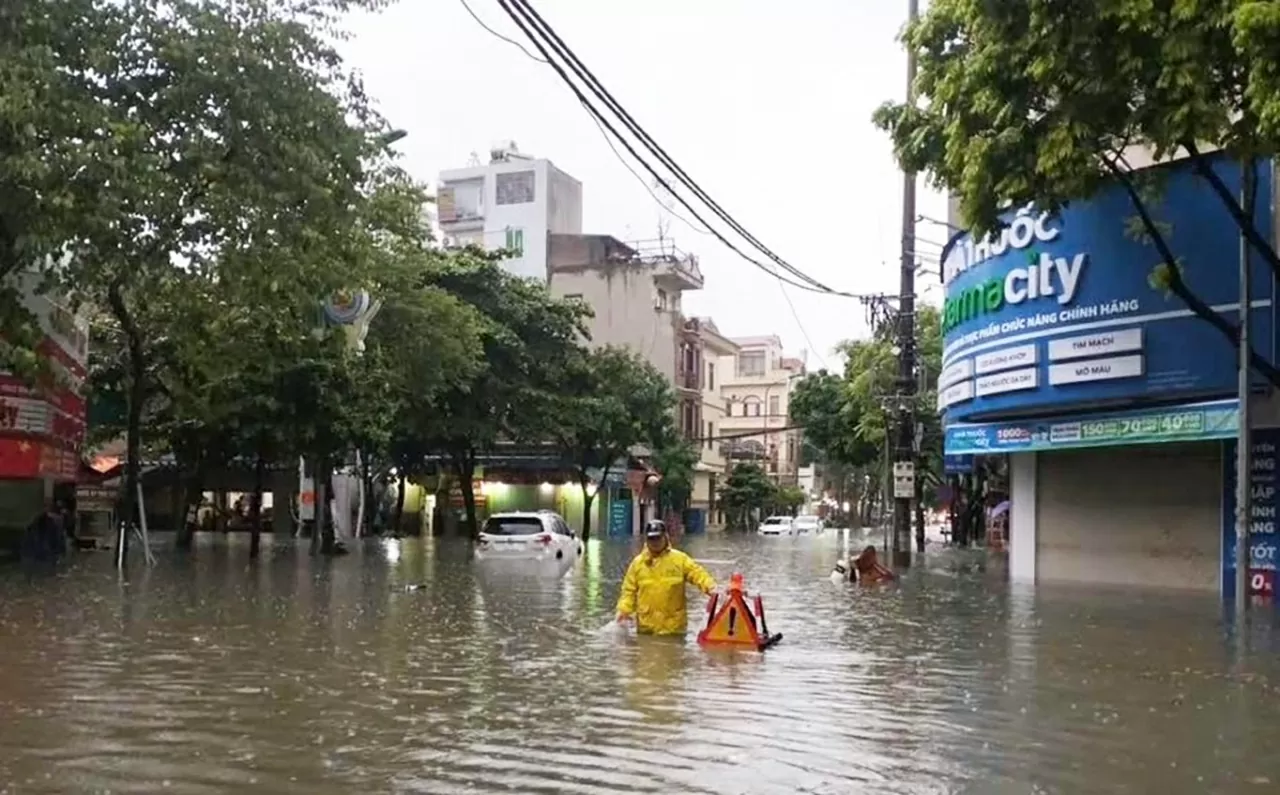 Trên tuyến phố Tô Hiệu, nước ngập sâu, Công nhân công ty TNHH thoát nước Hà Nội khơi thông các nắp hố ga giúp sớm thoát nước nhanh. (Ảnh: Đào Hằng)