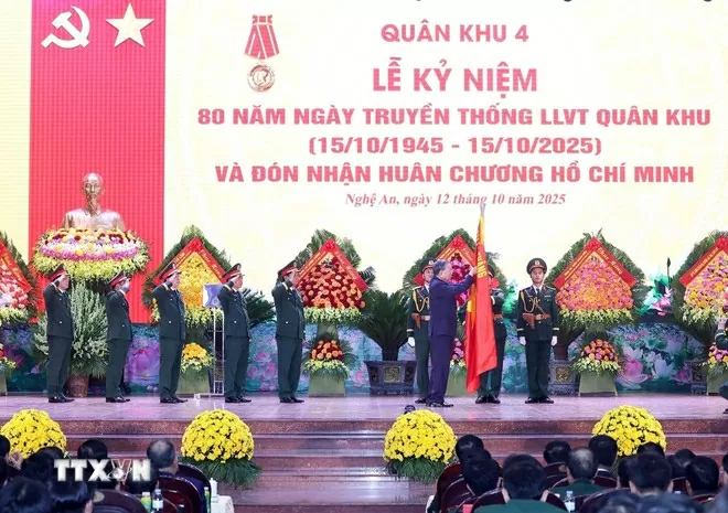 Tổng Bí thư Tô Lâm gắn Huân chương Hồ Chí Minh lên lá cờ truyền thống của Quân khu 4. (Ảnh: Thống Nhất/TTXVN)