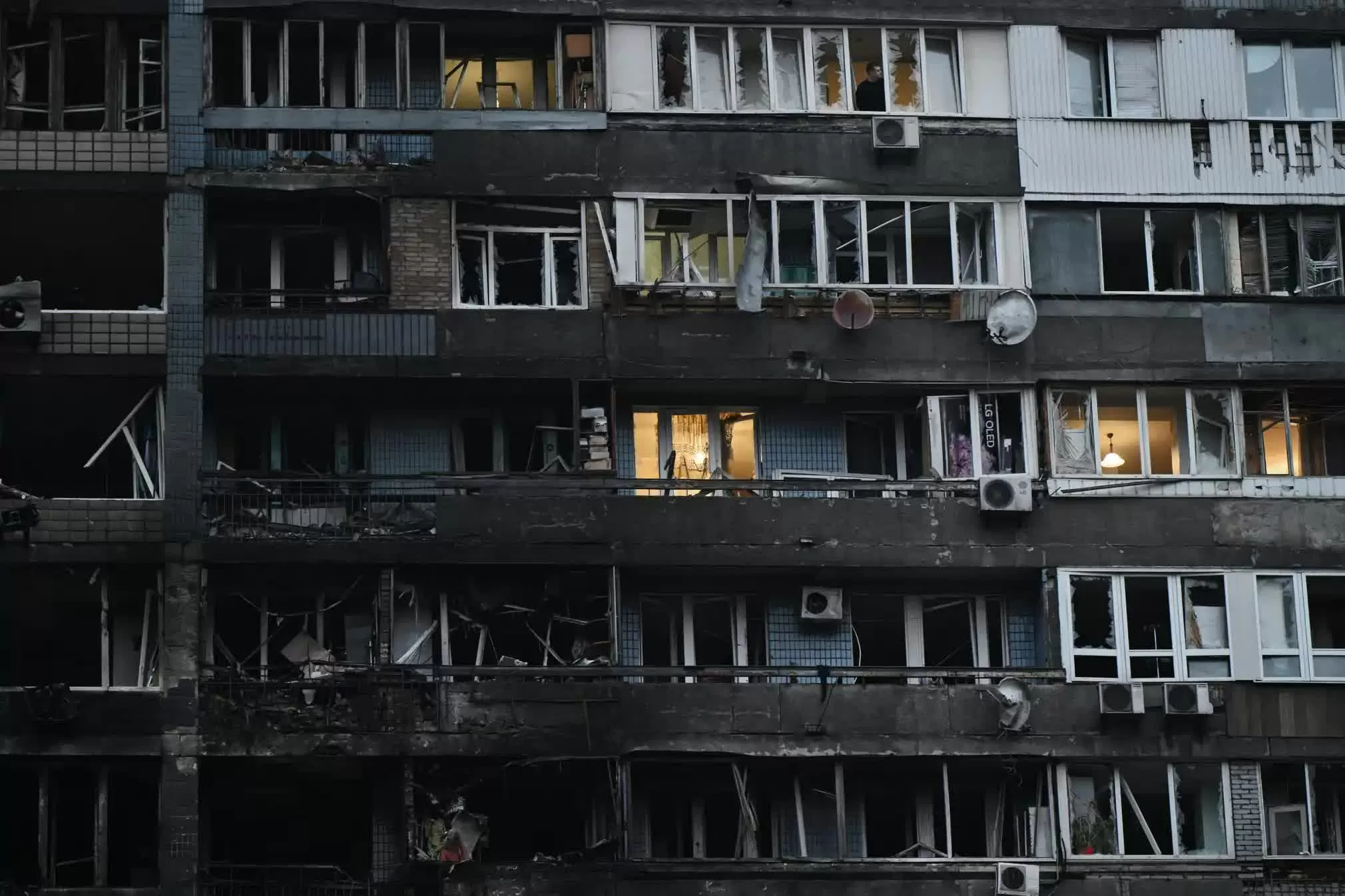 Một người đàn ông nhìn ra ngoài từ khung cửa sổ vỡ nát của một tòa nhà dân cư bị hư hại trong các đợt tấn công bằng máy bay không người lái và tên lửa của Nga nhằm vào Kyiv. Thủ đô của Ukraine đã chìm trong bóng tối vào rạng sáng thứ Sáu sau một cuộc “tấn công quy mô lớn”, theo mô tả của không quân Ukraine, khi Nga dồn dập tấn công vào cơ sở hạ tầng của Kyiv, khiến nguồn cung cấp nước và điện bị cắt đứt và gây ra hỏa hoạn tại một tòa chung cư cao tầng. (Nguồn: The Guardian)