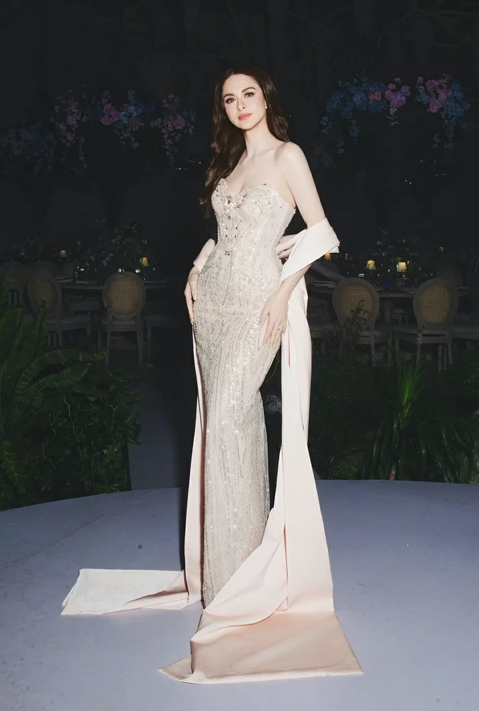 Marian Rivera diện đầm corset nhấn eo, được may riêng hơn hai tháng trước, đính hơn 1.000 viên đá pha lê và cườm bạc. Nhà thiết kế Trà Linh chuẩn bị thêm khăn choàng lụa màu kem sữa để hoàn thiện tổng thể trang phục.