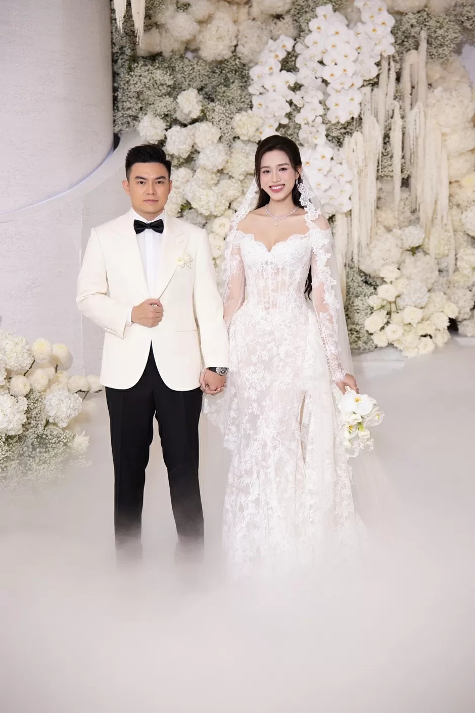 Trước lễ cưới nhiều tháng, Hoa hậu Đỗ Thị Hà cùng stylist Trần Nhật Duy đặt hàng nhiều nhà thiết kế để chuẩn bị cho ngày trọng đại. Khi đón khách, cô dâu xuất hiện cùng đầm đuôi cá, kiểu dáng trễ vai của NTK Phương Linh.