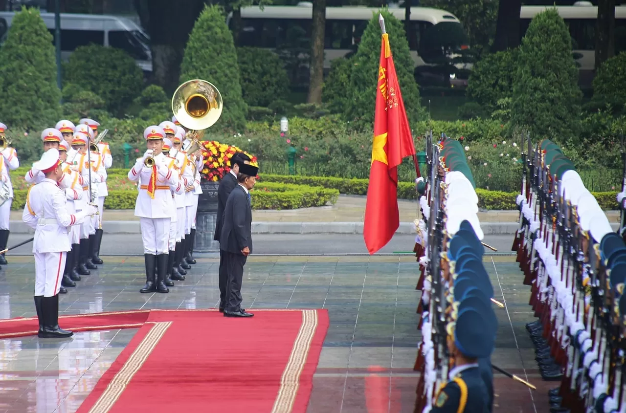 Chủ tịch nước Lương Cường và Quốc vương Brunei cúi chào Quân kỳ Quyết thắng. (Ảnh: Thành Long)
