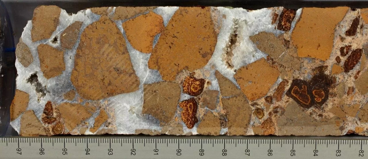 Lõi đá breccia dung nham được gắn kết bởi khoáng chất canxi cacbonat trắng, thu thập tại Địa điểm IODP U1557 dưới đáy Nam Đại Tây Dương. (Nguồn: IODP JRSO)