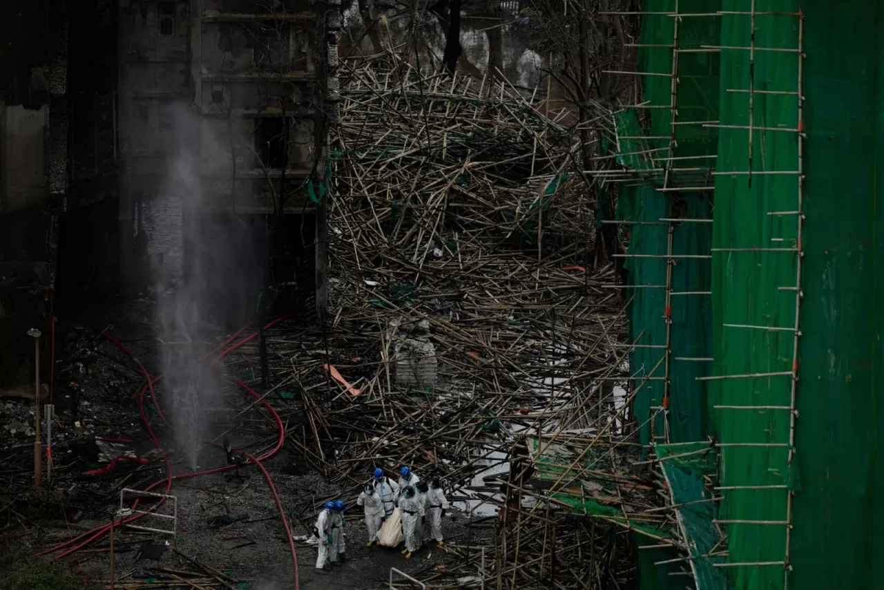 Lực lượng cứu hộ đưa một thi thể đi qua giàn giáo tre bị sập sau vụ hỏa hoạn chết người tại Wang Fuk Court, một khu nhà ở tại quận Tai Po thuộc khu vực Tân Giới. Các quan chức Hong Kong và Bắc Kinh đã cảnh báo về những gì họ gọi là các “thế lực bên ngoài” đang tìm cách lợi dụng vụ cháy chung cư chết người xảy ra vào tuần trước để gây bất ổn chính trị, trong khi lực lượng cứu nạn cho biết ít nhất 159 người đã được xác nhận thiệt mạng. (Nguồn: The Guardian)