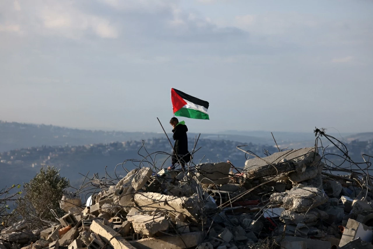 Một cậu bé vẫy lá cờ Palestine trên đống đổ nát của ngôi nhà thuộc gia đình Malik Ismail Salem tại làng Bizarya, gần thành phố Nablus ở Bờ Tây. Mười bốn quốc gia, trong đó có Anh, Canada và Đức, đã lên án việc nội các an ninh Israel phê duyệt 19 khu định cư mới tại Bờ Tây bị chiếm đóng, cho rằng động thái này vi phạm luật pháp quốc tế và có nguy cơ làm gia tăng bất ổn. (Nguồn: EPA) Một cậu bé vẫy lá cờ Palestine trên đống đổ nát của ngôi nhà thuộc gia đình Malik Ismail Salem tại làng Bizarya, gần thành phố Nablus ở Bờ Tây. Mười bốn quốc gia, trong đó có Anh, Canada và Đức, đã lên án việc nội các an ninh Israel phê duyệt 19 khu định cư mới tại Bờ Tây bị chiếm đóng, cho rằng động thái này vi phạm luật pháp quốc tế và có nguy cơ làm gia tăng bất ổn. (Nguồn: EPA)