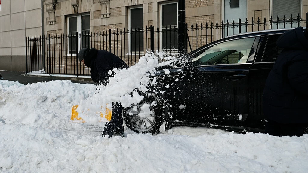 Một người đàn ông đang đào xe của mình ra khỏi đống tuyết ở thành phố New York, Mỹ, ngày 26 tháng 1 năm 2026. /VCG