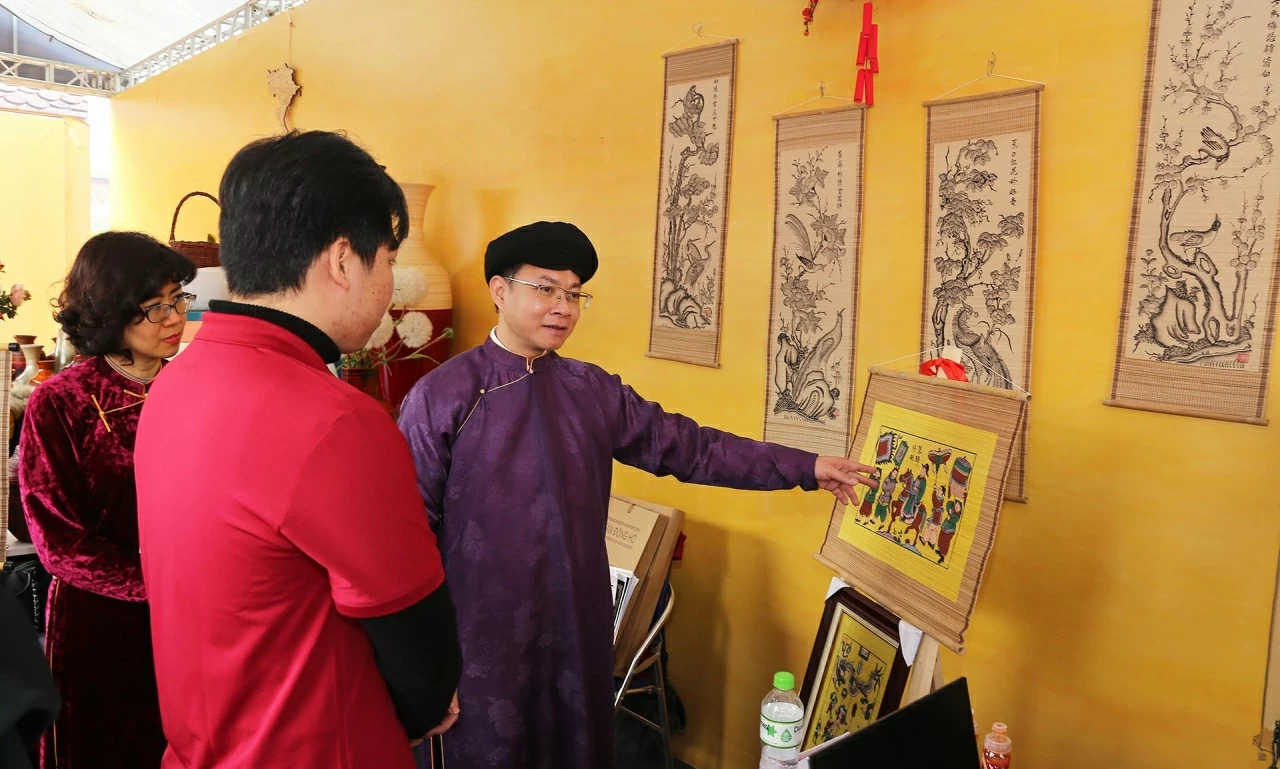 Các đại biểu thưởng thức văn hóa trà và xem tranh Đông hồ. (Ảnh: Thành Long)