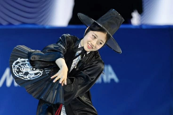 Bên cạnh các nội dung tranh huy chương, chương trình Exhibition Gala cũng thu hút sự chú ý với những tiết mục mang đậm dấu ấn văn hóa. Vận động viên Hàn Quốc Lee Hae-in hóa thân thành hình tượng “saja” - hình tượng thần chết trong văn hóa dân gian Hàn Quốc. Trong trang phục durumagi truyền thống, đội mũ gat và sử dụng quạt xếp làm đạo cụ, Lee kết hợp yếu tố văn hóa Á Đông với phong cách dàn dựng hiện đại trên sân băng. Phần trình diễn được cho là lấy cảm hứng từ tác phẩm hoạt hình của Netflix KPop Demon Hunters. Theo Korea JoongAng Daily, dù xếp hạng tám ở nội dung đơn nữ, cô vẫn được ban tổ chức lựa chọn tham gia gala. Đây là chương trình biểu diễn tổng kết dành cho các vận động viên được đánh giá cao về dấu ấn chuyên môn và phong cách trình diễn. (Nguồn: Korea Joongang Daily)
