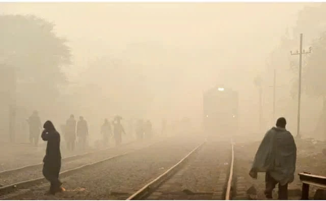 Người dân đi bộ băng qua đường ray xe lửa trong điều kiện sương mù ô nhiễm dày đặc tại Lahore, Pakistan. (Nguồn: AFP)