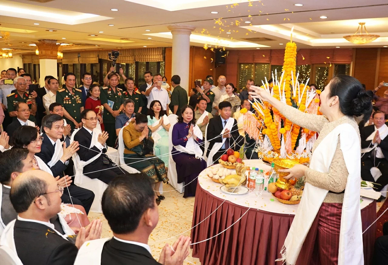 Các đại biểu thực hiện nghi Lễ buộc chỉ cổ tay (còn gọi là lễ Sou khoẳn) là phong tục tập quán tâm linh gắn với đời sống của người dân Lào. (Ảnh: Thành Long)