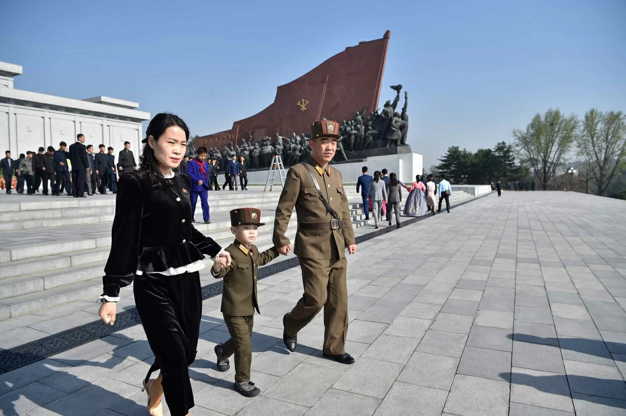 Một binh sĩ Triều Tiên cùng gia đình rời đi sau khi dâng hoa tưởng niệm tại tượng đài của cố lãnh tụ Kim Il-sung nhân dịp kỷ niệm 114 năm ngày sinh của ông. (Nguồn: Getty Images)