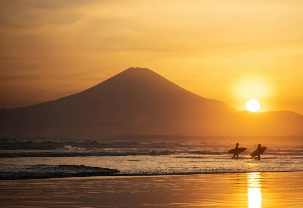 Những người lướt sóng rời khỏi mặt nước tại Fujisawa, Nhật Bản, khi mặt trời lặn phía sau Mount Fuji vào thứ Bảy, ngày 11 tháng 4. (Nguồn: Getty Images)
